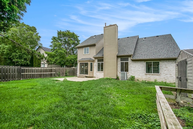 rear view of property with a lawn, central AC, and a patio area