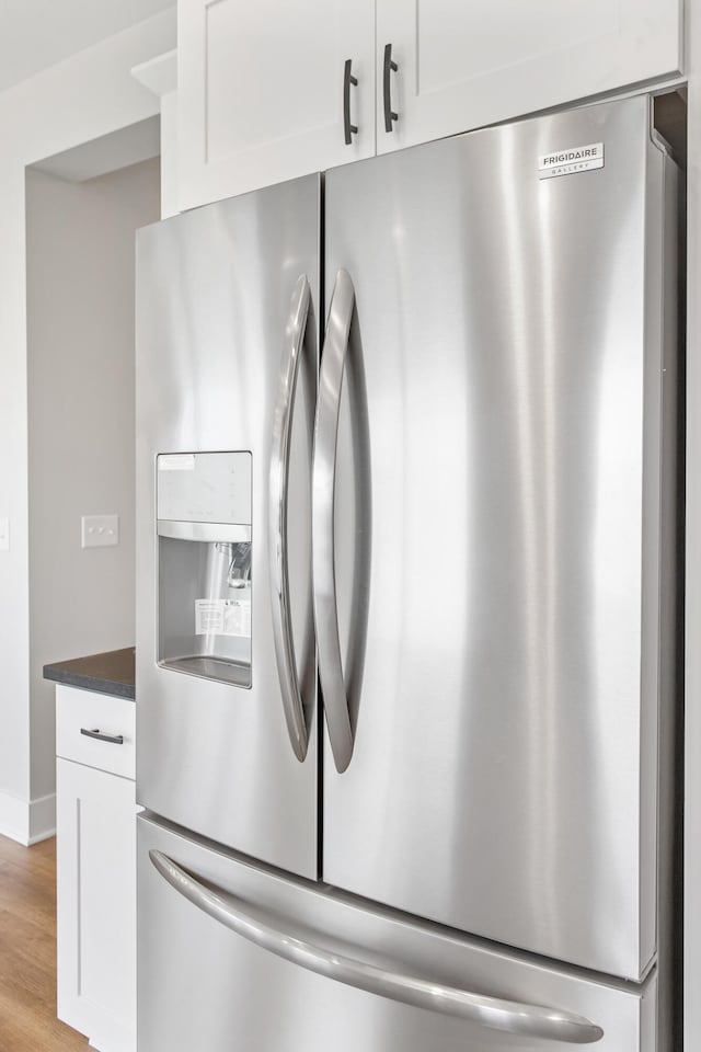 9139 Perry Ct, Zeeland, MI 49464 - kitchen view of stainless steel fridge with ice dispenser, white cabinets, dark countertops, and wood finished floors