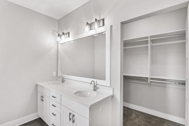9139 Perry Ct, Zeeland, MI 49464 - bathroom featuring double vanity, baseboards, and a walk in closet