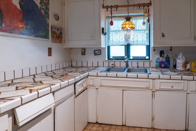 kitchen featuring white cabinets, decorative light fixtures, tile counters, and sink