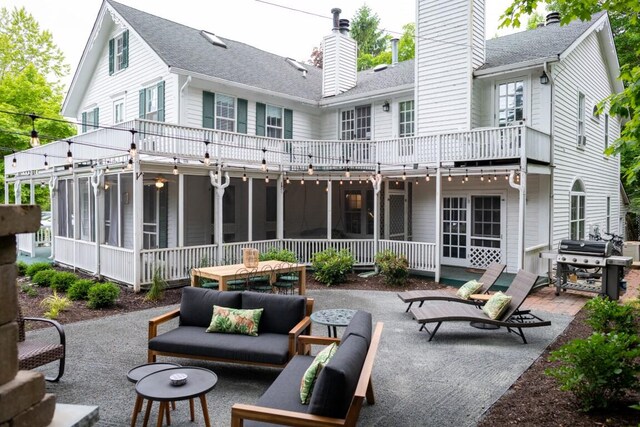 back of house with outdoor lounge area, a patio, a balcony, and a sunroom