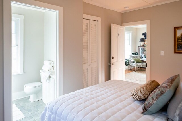 bedroom featuring connected bathroom, a closet, and light tile patterned flooring