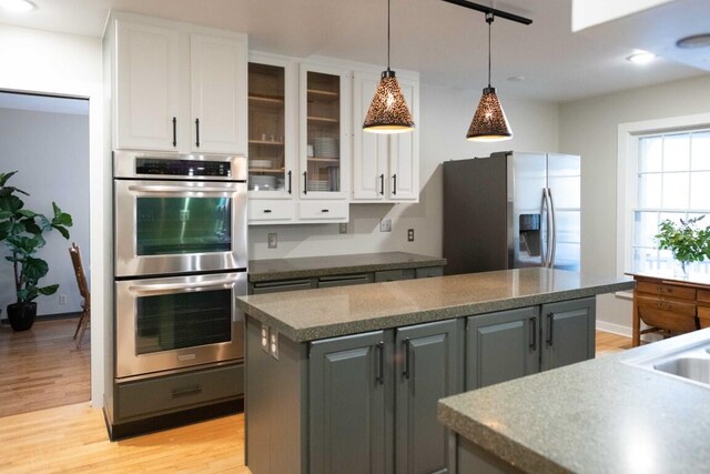 kitchen featuring gray cabinetry, white cabinetry, pendant lighting, light hardwood / wood-style floors, and appliances with stainless steel finishes