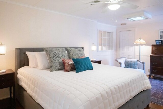 bedroom with dark hardwood / wood-style flooring, ceiling fan, and crown molding