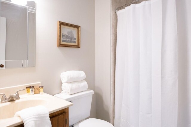 bathroom featuring a shower with curtain, vanity, and toilet