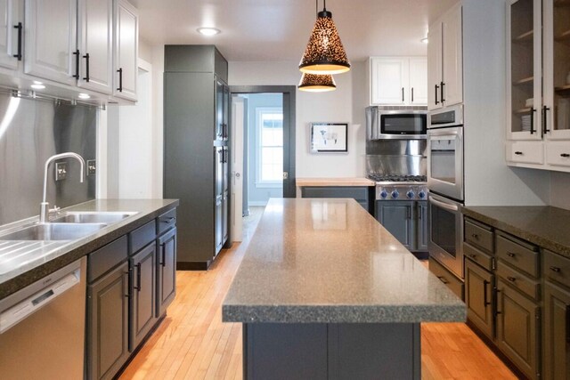 kitchen with a center island, sink, stainless steel appliances, white cabinets, and light wood-type flooring