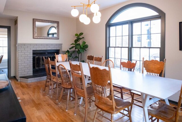 dining room with a chandelier, light hardwood / wood-style floors, and a brick fireplace