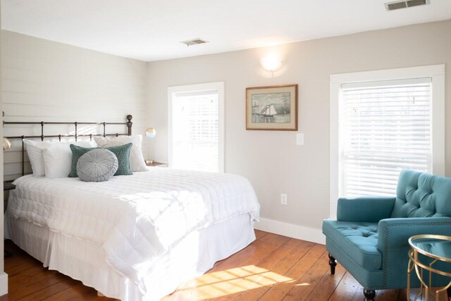 bedroom with multiple windows and hardwood / wood-style flooring