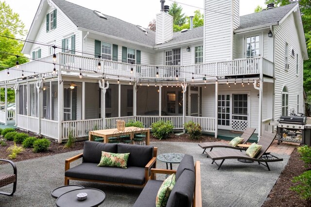 rear view of house with outdoor lounge area, a balcony, a patio area, and a sunroom