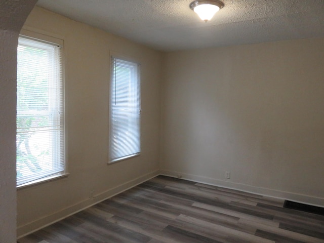 empty room with dark hardwood / wood-style flooring and a textured ceiling