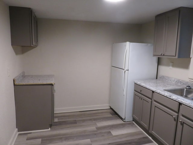 kitchen featuring gray cabinets, sink, light hardwood / wood-style flooring, and white refrigerator