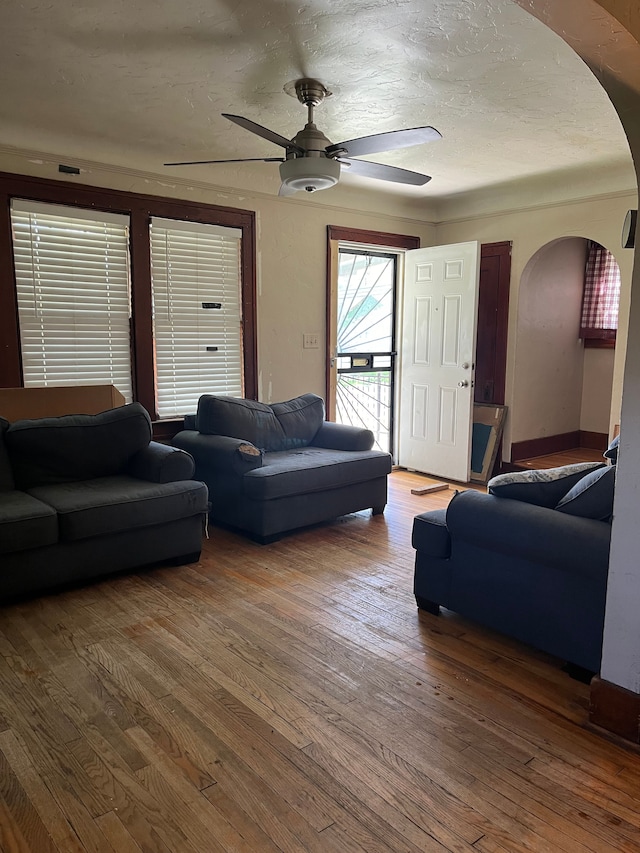 living room featuring hardwood / wood-style flooring, ceiling fan, and a textured ceiling