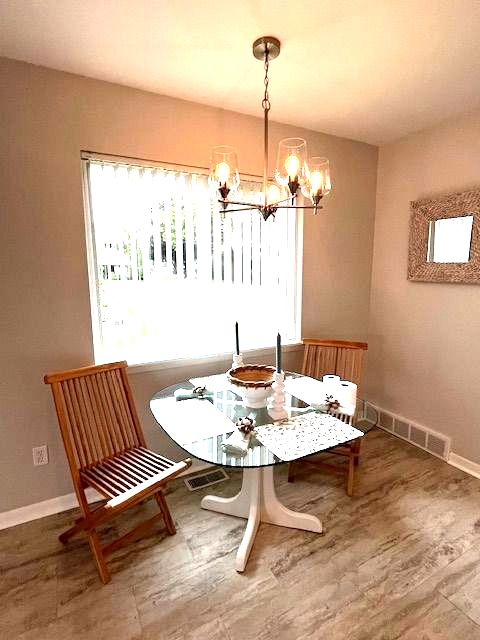 dining space with hardwood / wood-style floors and a notable chandelier