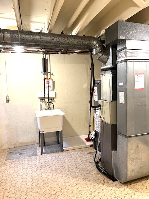 utility room featuring heating unit, gas water heater, sink, and water heater