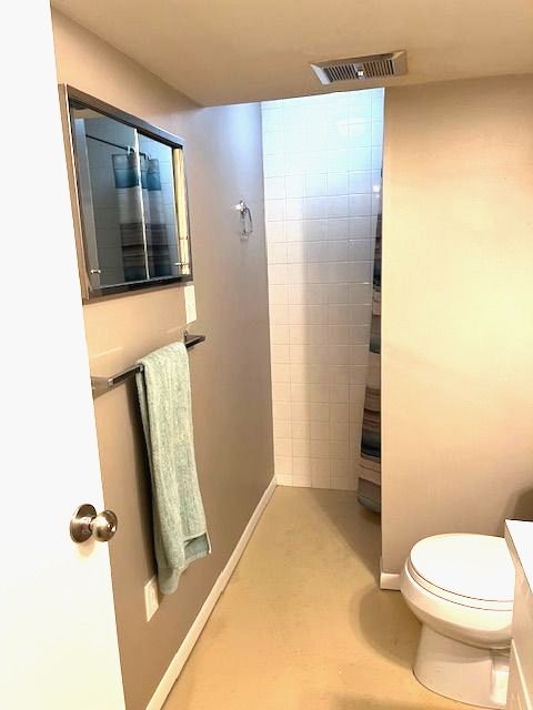 bathroom with a tile shower and toilet