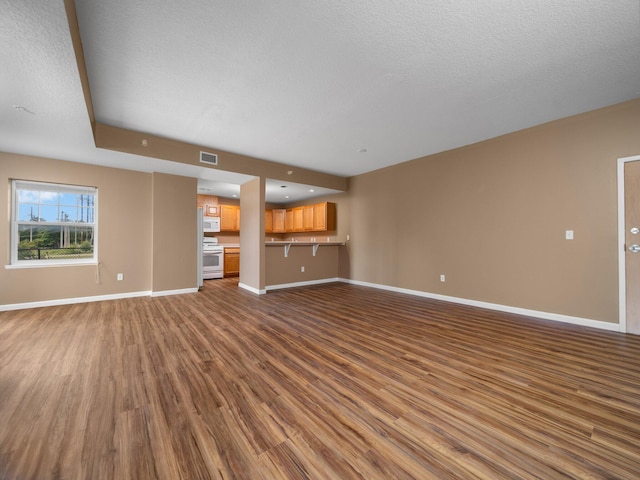 unfurnished living room featuring wood-type flooring and a textured ceiling