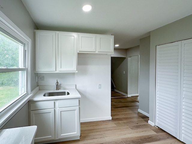 kitchen with white cabinets, light hardwood / wood-style floors, a healthy amount of sunlight, and sink