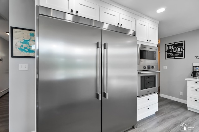 kitchen with white cabinetry, built in appliances, and light hardwood / wood-style floors