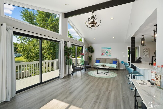 living room with beamed ceiling, an inviting chandelier, high vaulted ceiling, and light wood-type flooring