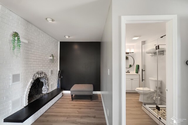 interior space featuring brick wall, sink, and light hardwood / wood-style flooring