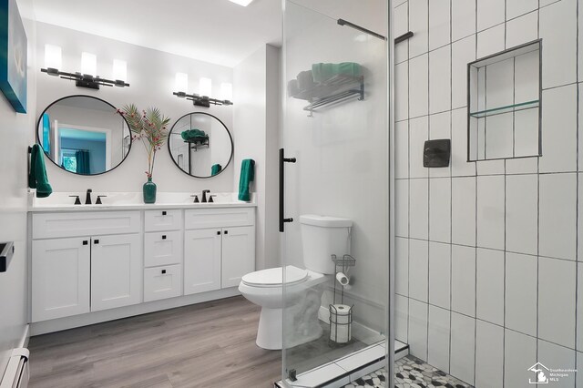 bathroom with vanity, a baseboard heating unit, toilet, and a tile shower