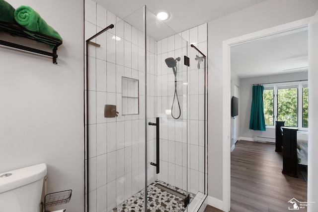 bathroom with a baseboard radiator, wood-type flooring, walk in shower, and toilet