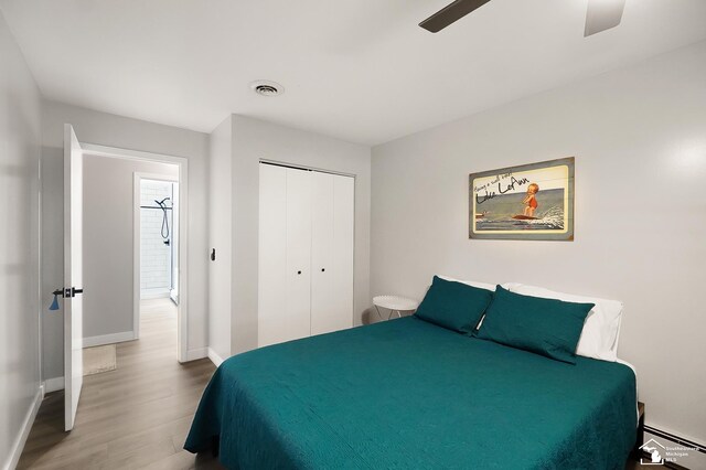 bedroom featuring a baseboard radiator, wood-type flooring, ceiling fan, and a closet