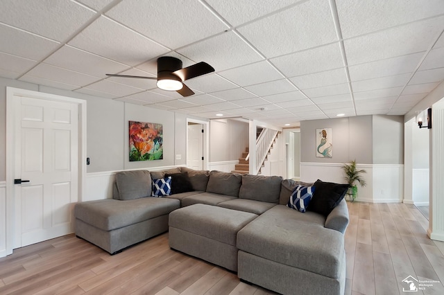 living room with ceiling fan, light hardwood / wood-style floors, and a drop ceiling