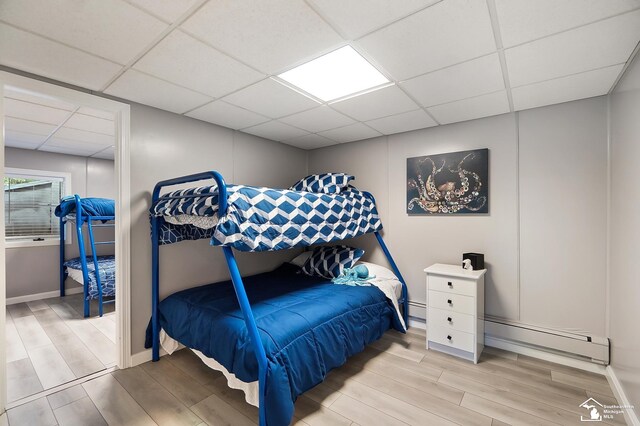 bedroom featuring a baseboard radiator, a paneled ceiling, and light hardwood / wood-style flooring