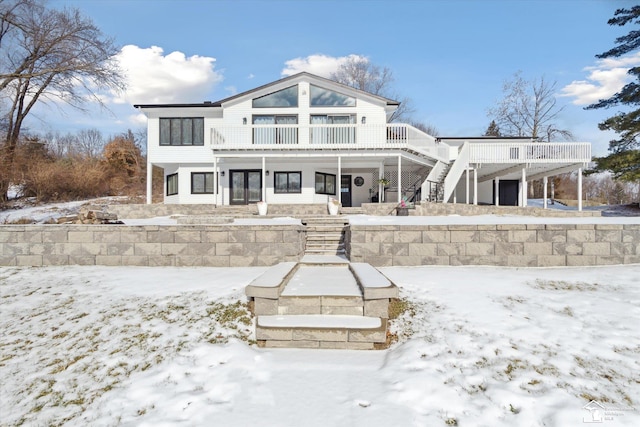 snow covered rear of property with a balcony