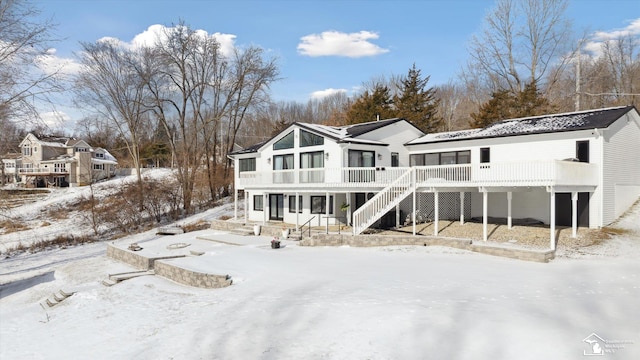 snow covered house with a wooden deck and covered porch