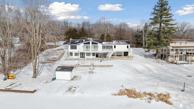 snow covered house featuring a storage shed