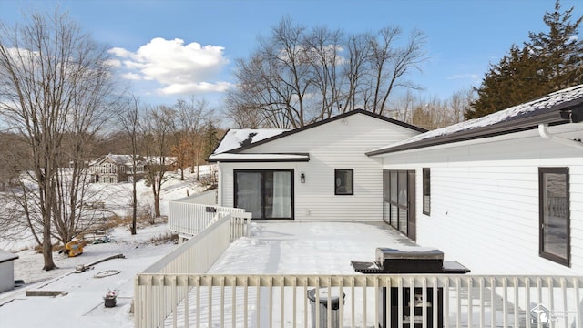 snow covered back of property featuring a deck