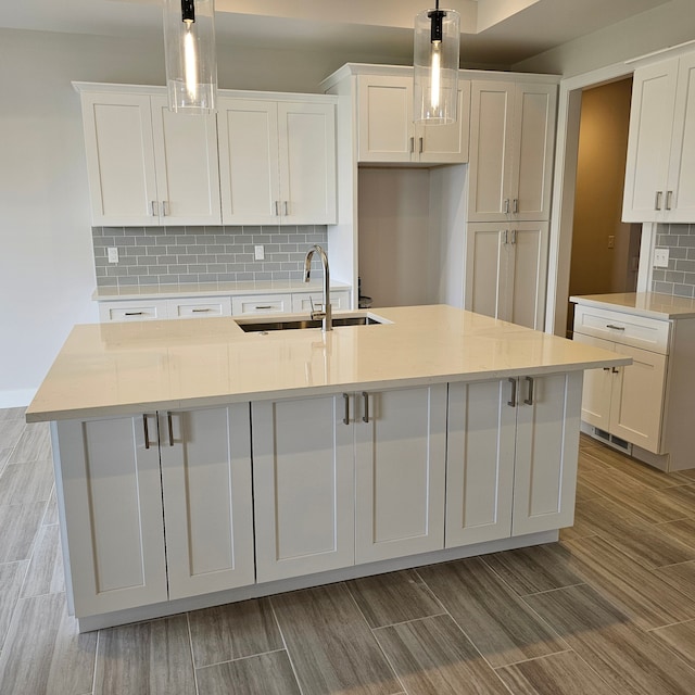 kitchen featuring an island with sink, white cabinetry, and pendant lighting