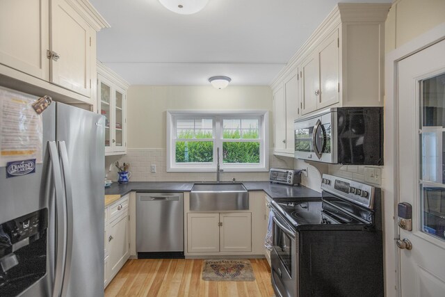 21945 Howell Dr, Cassopolis, MI 49031 - kitchen with stainless steel appliances, a sink, light wood-style flooring, backsplash, and dark countertops