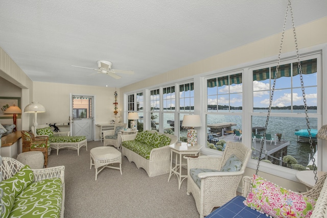 sunroom / solarium with ceiling fan and a water view