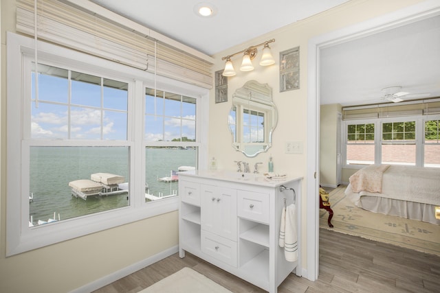 bathroom featuring hardwood / wood-style flooring, ceiling fan, a water view, and a wealth of natural light