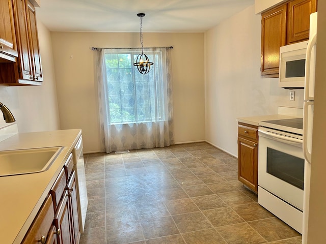 kitchen featuring sink, pendant lighting, white appliances, and a notable chandelier