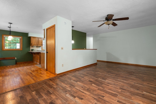 unfurnished living room featuring a textured ceiling, ceiling fan, and dark wood-type flooring