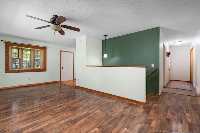 empty room featuring a textured ceiling, ceiling fan, and dark wood-type flooring