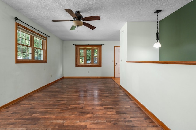 unfurnished room featuring a healthy amount of sunlight, a textured ceiling, and dark wood-type flooring