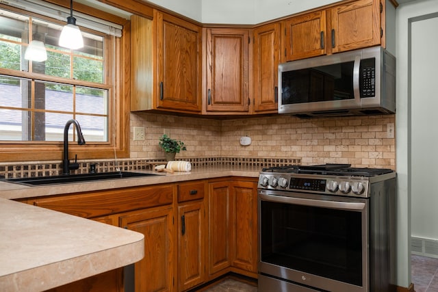 kitchen with tasteful backsplash, stainless steel appliances, sink, decorative light fixtures, and dark tile patterned flooring