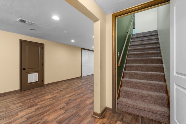 staircase featuring hardwood / wood-style floors and a textured ceiling