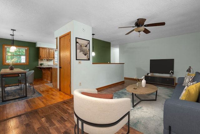 living room featuring ceiling fan, dark hardwood / wood-style flooring, and a textured ceiling