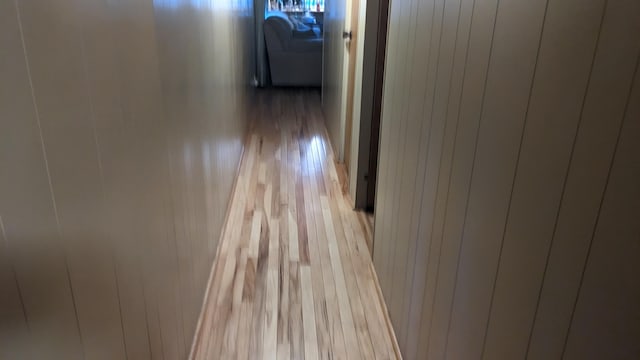 corridor with wooden walls and light hardwood / wood-style flooring