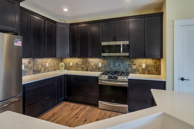 kitchen with tasteful backsplash, appliances with stainless steel finishes, and light hardwood / wood-style flooring