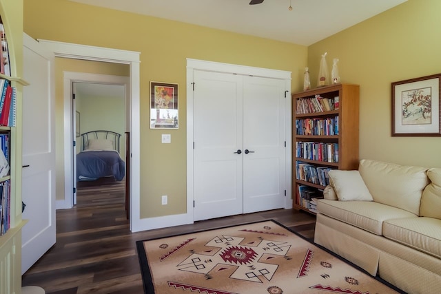 sitting room with ceiling fan and dark wood-type flooring