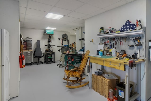 misc room with concrete flooring, a workshop area, and a drop ceiling