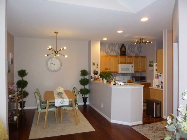 kitchen featuring kitchen peninsula, white appliances, a chandelier, and dark wood-type flooring