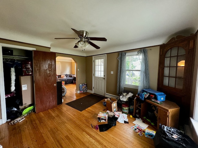 living room with ceiling fan, wood-type flooring, and a baseboard heating unit